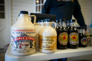 Bottles of Jirik Family Farms maple syrup sit lined up on a table at the Cannon Valley Farmers' Market